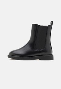 Czarny skórzany botek za kostkę z elastycznymi bocznymi panelami, zaokrąglonym noskiem i niską, teksturowaną gumową podeszwą. Posiada pętlę do łatwego zakładania.