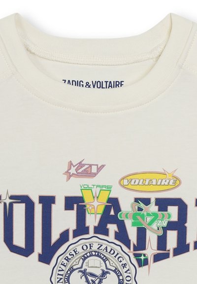 Sweatshirt de couleur crème avec un col rond, arborant des imprimés graphiques multicolores incluant "VOLTAIRE" et des logos dans divers designs.
