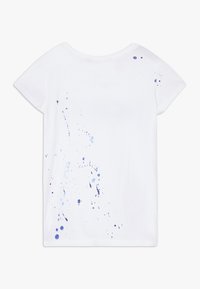 Biała koszulka z krótkim rękawem, z niebieskimi plamami farby na plecach. Miękka bawełniana tkanina, luźny krój, okrągły dekolt.