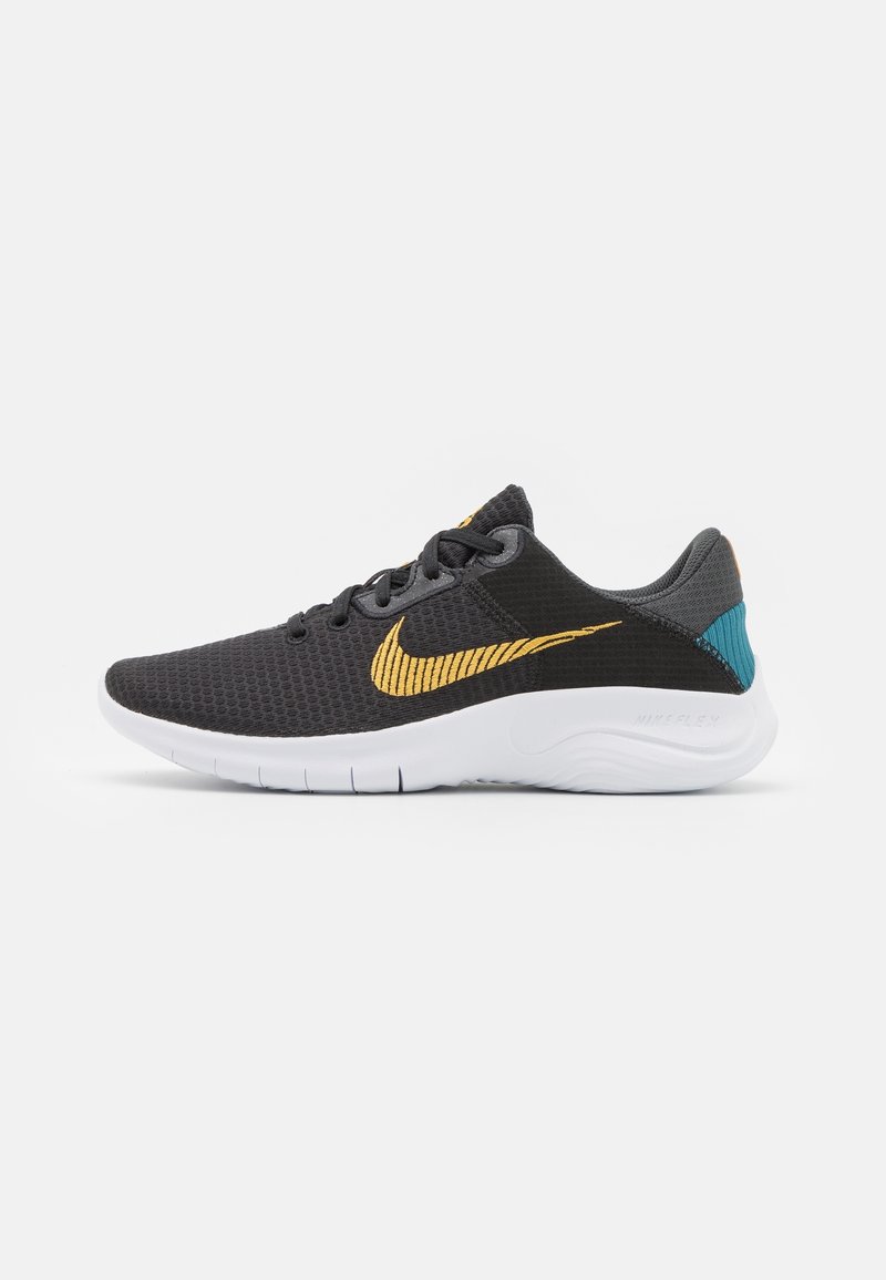 Chaussure de sport noire avec le logo Nike jaune, semelle blanche, lacets gris foncé et accent bleu sarcelle au talon, vue de côté.