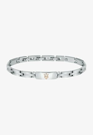 Bracelet en métal argenté avec des segments plats et liés alternés ; la plaque centrale rectangulaire présente un accent de logo en or. Texture lisse dans l'ensemble.