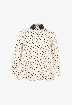 Blouse crème avec des pois noirs, manches longues bouffantes, devant à boutons et col en dentelle noire décoratif.