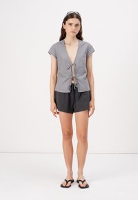 Gray striped short-sleeve top with a tie-front detail, paired with black shorts. The fabric appears soft and lightweight. Simple design.