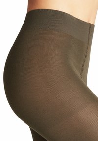 Braune Strumpfhosen mit strukturiertem Rippdesign und einem breiten Bund. Das Material wirkt leicht transparent und zeigt ein nahtloses Design.