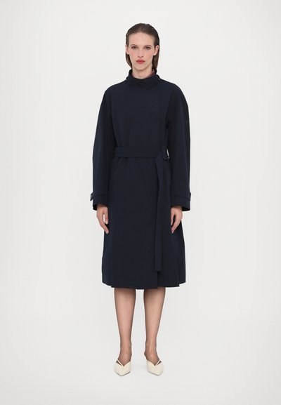 Ein marineblaues Kleid aus weichem Stoff, mit hohem Kragen, langen Ärmeln, Gürtel und einem knielangen Saum. Einfaches, modernes Design ohne Muster.
