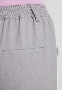 Grå joggbyxor med texturerad yta, med elastisk midja, en diskret bakficka och kontrasterande sidodetaljer.