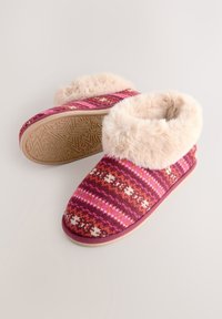 Chaussons doux à motifs roses avec un bord en fausse fourrure, une semelle en caoutchouc et un design texturé complexe sous la semelle pour une meilleure adhérence.