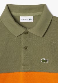 Grøn og orange Lacoste polo shirt med ribbet krave, tre-knap lukning og broderet krokodillelogo. Struktureret stof.