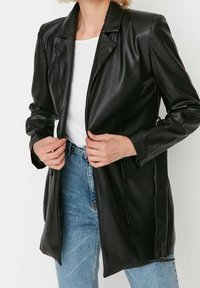 Zwarte neplederen blazer met een sluiting met één knop, geknipte revers en voorzakken. Heeft een gladde textuur en een getailleerd ontwerp.