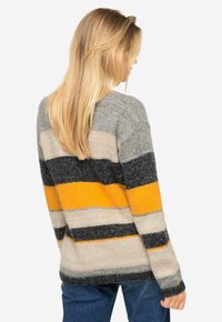 Maglione lavorato a maglia con strisce orizzontali in grigio, nero, beige e giallo. Vestibilità ampia con maniche lunghe e polsini a costine. Texture morbida.