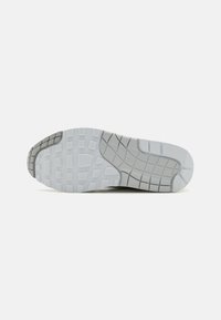 Podešev boty s texturovaným designem, převážně šedá; obsahuje flexibilní gumový materiál a složitý vzor dezénu pro lepší trakci.