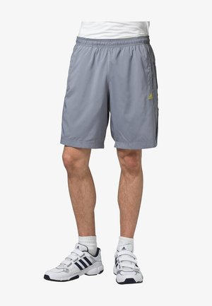 Light gray athletic shorts with an elastic waistband, side pockets, and a small green logo. Worn with white shoes featuring blue accents.
