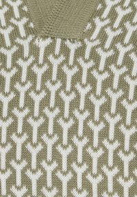 Gros plan d'un tissu tricoté avec un motif en forme de Y répété en vert olive et blanc et détail du col en V.