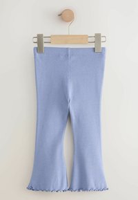 Lichtblauwe geribde legging met een uitlopende onderkant en gegolfde randen, opgehangen aan een houten clip tegen een neutrale achtergrond.