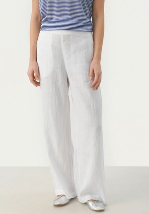 Weiße Leinen-Hosen mit weitem Bein und glatter Textur, kombiniert mit einem blau-weiß gestreiften Oberteil und silbernen Ballerinas.