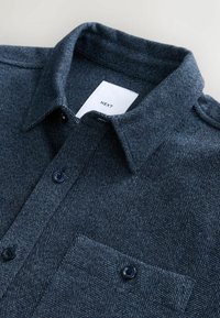 Cămașă bleumarin cu model herringbone, realizată dintr-un material texturat, având guler cu nasturi, nasturi negri și un buzunar pe piept cu eticheta "NEXT."