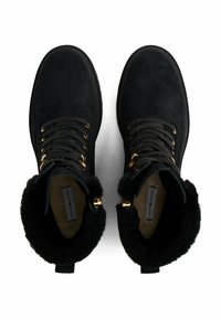 Bottines en suède noir avec hardware doré, design à lacets, doublure en fourrure et semelle plate. Comprend un col rembourré pour plus de confort.