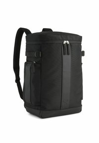 Sac à dos noir en tissu durable, de forme cylindrique, dotée de deux compartiments zippés, d'une poche latérale et de bretelles ajustables.