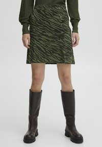 Grön och svart randig kjol med tigerstrimmor, med rak form och fem knappdetaljer framtill. Slät tyg och midilängd.