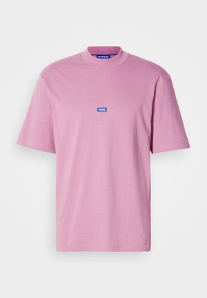 T-shirt rosa a maniche corte con collo rotondo, caratterizzato da un piccolo logo rettangolare blu con l'etichetta "HUGO" sul petto. Realizzato in tessuto morbido.