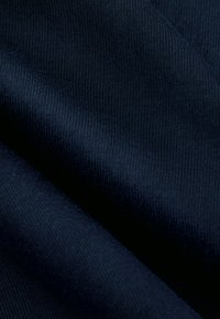 Marineblauwe stof met een gladde textuur en een geribd patroon, met zachte plooien die flexibiliteit en zachtheid aangeven.