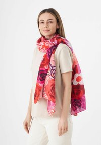 Écharpe florale colorée affichant des nuances de rouge et de rose, en tissu léger, avec un design fluide et des motifs floraux, drapée élégamment autour du cou.