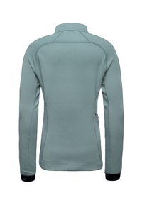 Světle modrá sportovní bunda s vysokým límcem, dlouhými rukávy a kontrastními texturovanými manžetami. Obsahuje ploché švy a boční kapsu.