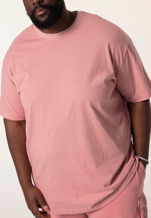 Camiseta de manga corta y cuello redondo en tejido de algodón de color rosa claro, con un corte relajado y una textura suave. Acentuada con una costura visible.