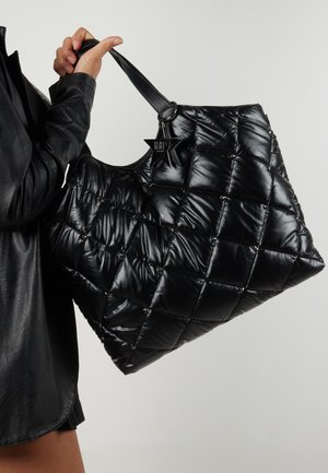 Zwarte, gewatteerde tote bag met een glanzende textuur, twee stevige handvatten en een stervormige hanger aan het handvat.