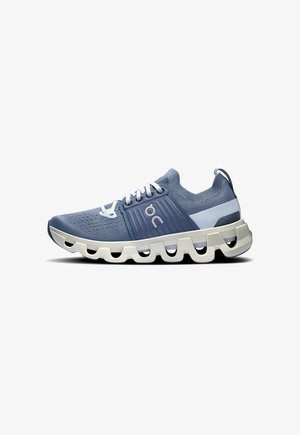 Light blue athletic shoe with a knit upper, white laces, and a thick, segmented white sole featuring cutouts for added flexibility.