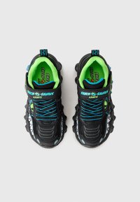 Black athletic shoes with green accents, blue laces, mesh material, and a textured sole. Features a dinosaur design and light-up details.
