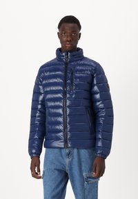 Navy Blousonjacke mit hohem Kragen, horizontalen Nähten, Reißverschluss vorne und an der Tasche, elastischen Bündchen und glänzender Oberfläche.
