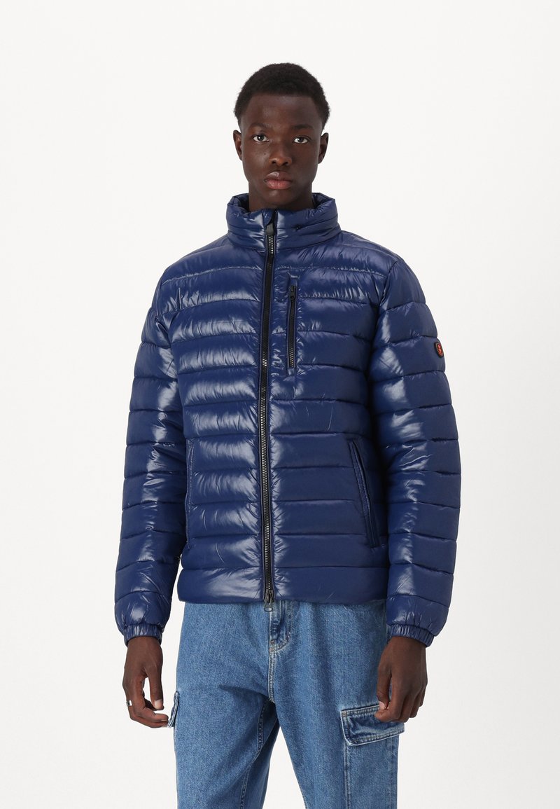 Navy Blousonjacke mit hohem Kragen, horizontalen Nähten, Reißverschluss vorne und an der Tasche, elastischen Bündchen und glänzender Oberfläche.