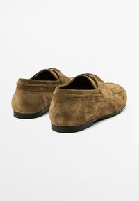 Brune loafers i ruskind med afrundet tå, blød tekstur og minimalistisk design. Sort gummisål og to dekorative syninger bagpå.