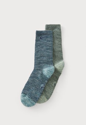Two pairs of socks in varying shades of blue and green. Textured fabric with ribbed design and reinforced heel and toe areas.