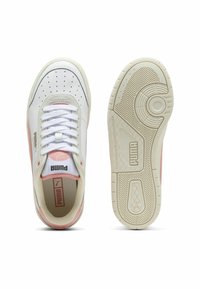 Fehér és világosszürke sportcipők rózsaszín akcentussal, sima bőr felsőrésszel, kerek perforációkkal, lapos fűzőkkel és strukturált gumitalpakkal.