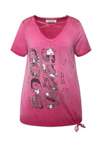 Vaaleanpunainen lyhythihainen T-paita V-päällä, jossa on sekoitus printtisuunnitelmia ja strasseja, säädettävä solmio helmassa ja tekstuuripinnat harteilla.