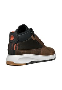 Zapatilla media alta de cuero marrón y malla negra con suela blanca. Presenta detalles naranja y paneles texturizados. Cierre con cordones.