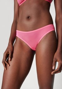 Culotte in rete rosa in stile bikini con una cintura morbida e copertura minima. Texture liscia, con un design senza cuciture e bordi in contrasto.