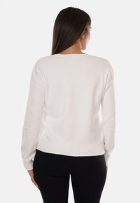 Maglione bianco a maniche lunghe con orlo e polsini a coste. Presenta una vestibilità ampia e un ampio scollo, realizzato in morbido tessuto lavorato a maglia.