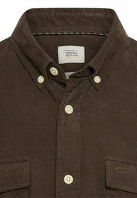 Bruine geruite overhemd met een kraag, voorzien van lichtkleurige knopen en een enkele borstzak. Label zichtbaar binnen de kraag.