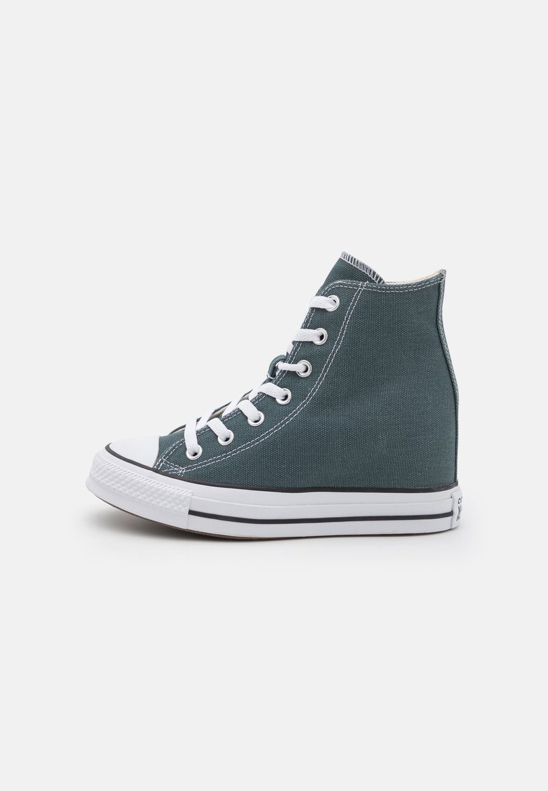 Basket montante en toile vert foncé avec semelle en caoutchouc blanche, bout renforcé et lacets blancs vue de côté sur fond blanc.