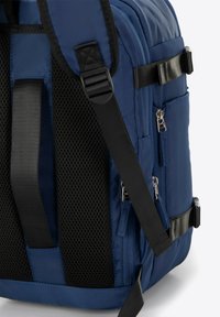 Námořnický modrý batoh s černými síťovými popruhy, metalovými zipy, několika kapsami a texturovanou látkou. Obsahuje spony a nastavitelné popruhy.