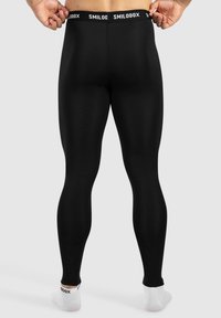 Maha leggings musta valmistatud venivast materjalist, millel on sile tekstuur, laia vöökoha ja "SMILODOX" brändinguga.