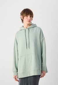 Overmaat mintgroene hoodie gemaakt van zachte stof, met een voorkantzak, verstelbare trekkoordcapuchon en ribgebreide manchetten.