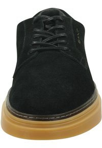 Schwarzer Wildlederschuh mit Schnürdesign, runder Zehe und einer sandfarbenen Gummisohle. Verfügt über minimale Nähte und eine glatte Textur im Obermaterial.