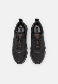 Baskets noires avec un accent texturé marron, dotées d'une tige en mesh, de lacets ronds et de détails de logo sur les côtés et la languette.