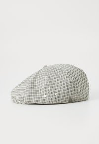 Platpet met een stoffen grijs-witte ruitjespatroon. Heeft een ronde kroon, een lichte rand en een metalen logo-accent.