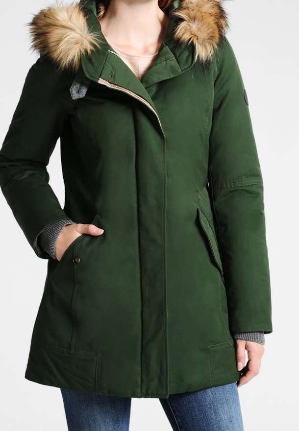 Grøn parka med en pelsforet hætte, lynlås og sidelommer. Har en glat tekstur og kontrasterende grå strikkede manchetter.