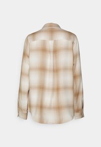 Camicia con bottoni in un leggero motivo a quadri marrone chiaro, con maniche lunghe, tessuto morbido e orlo curvo. Presenta uno small yoke posteriore.